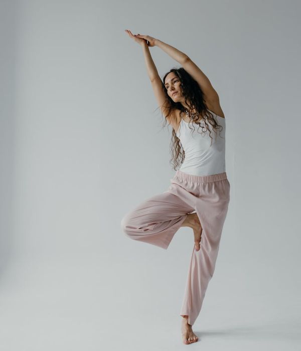 A woman in a peaceful stretching pose in a minimalist, dark studio.
